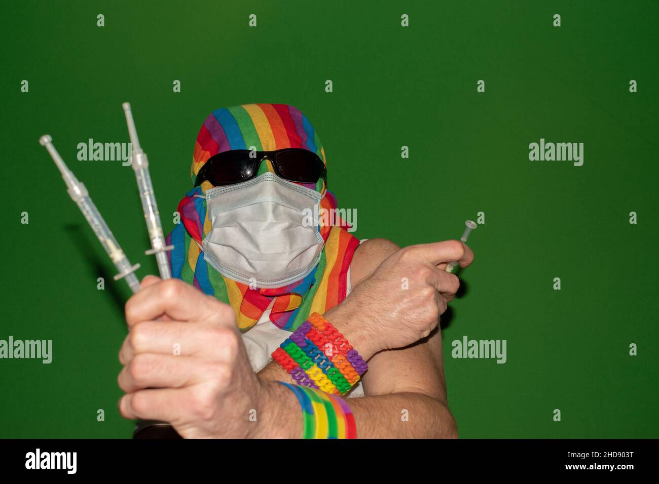 Vaduz, Liechtenstein, December 24, 2021 Person with a medical face mask and a gender rainbow flag is showing some syringes Stock Photo