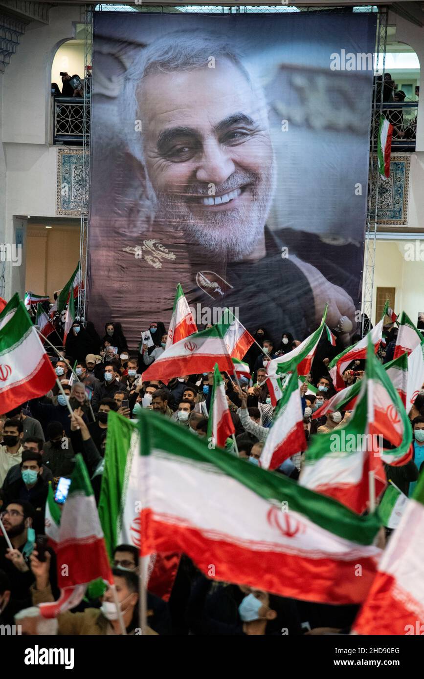 (1/3/2022) men wave the Iranian flag in front of a poster of the ...