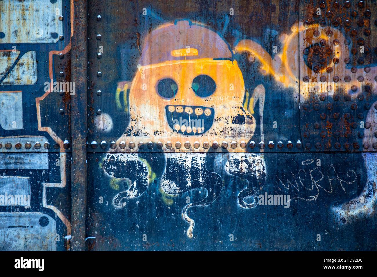 Street art. Weathered graffiti on a rusty metal surface. Stock Photo