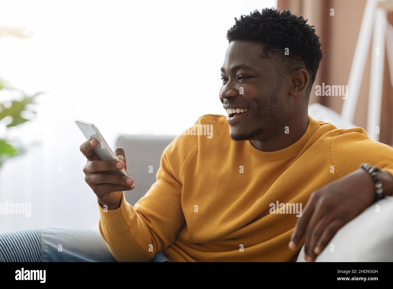 Happy black guy chatting with girlfriend, using cellphone at home Stock Photo