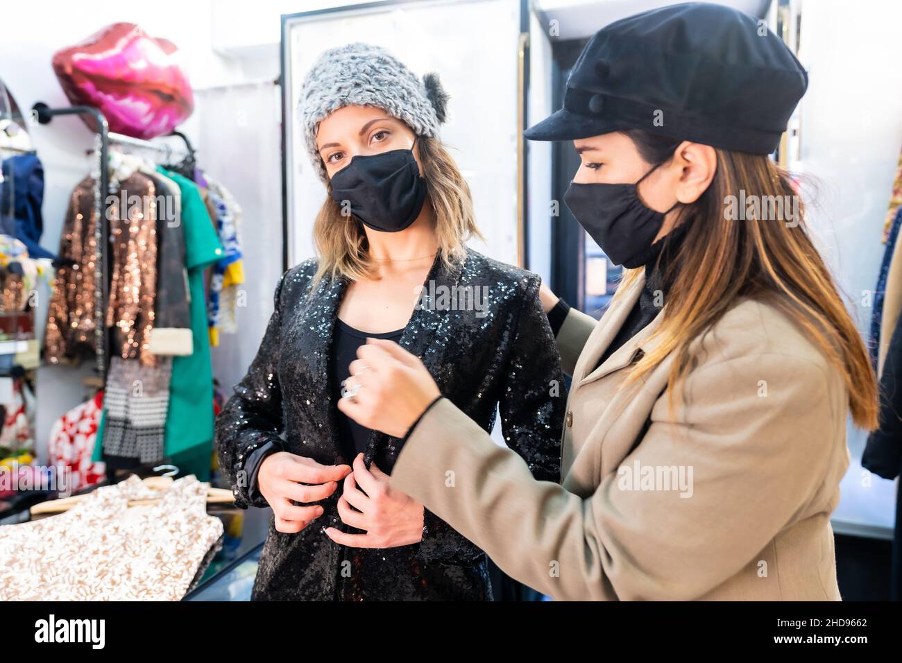 Employee and a client with masks in a luxury clothing store, security measures in the coronavirus pandemic, covid-19 Stock Photo