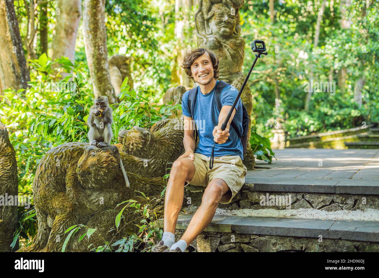 Selfie with monkeys. Young man uses a selfie stick to photo or video blog cute funny monkey. Travel selfie with wildlife in Bali Stock Photo - Alamy
