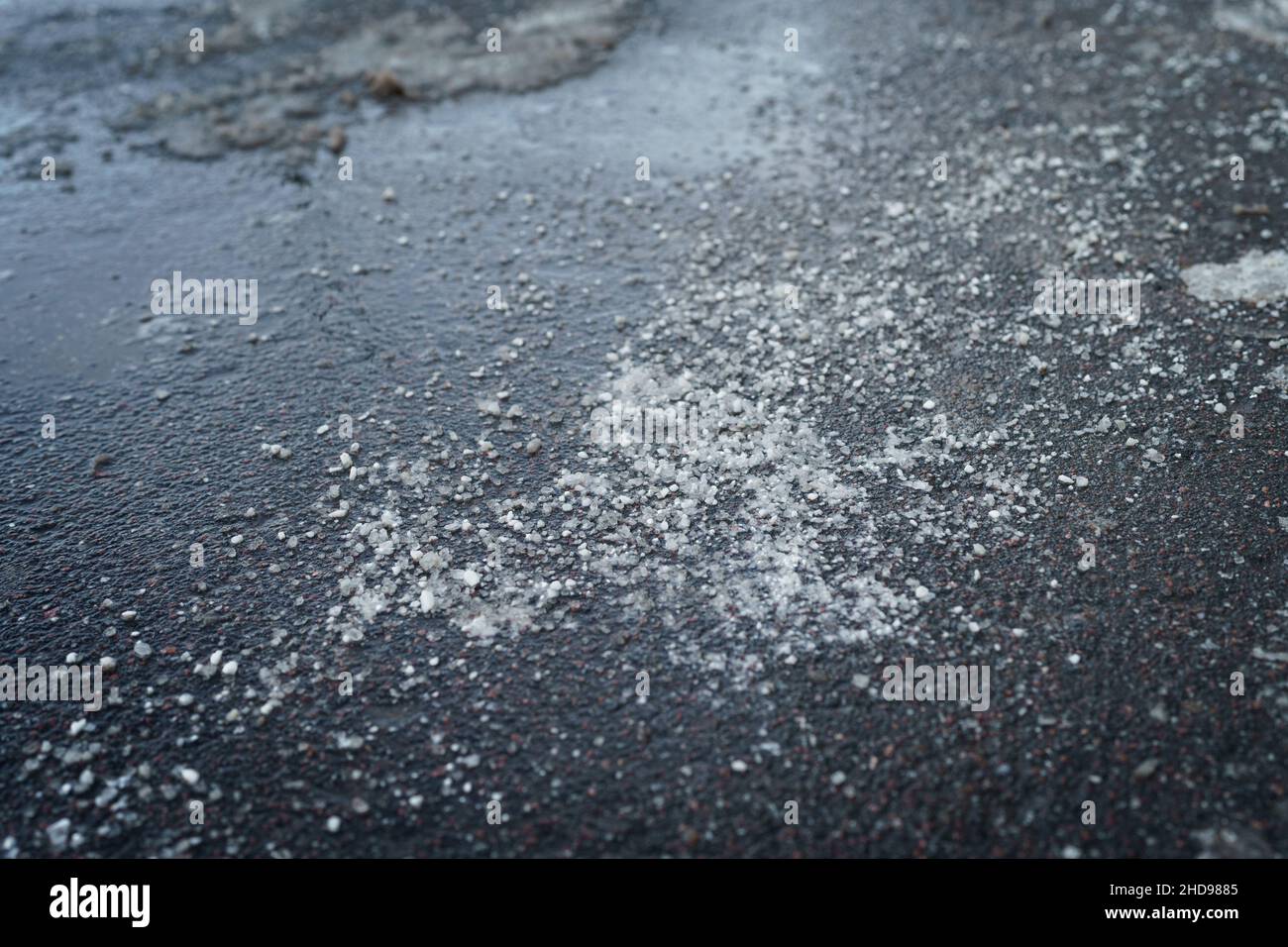 De-icing chemical reagent on road in winter time. Pavement is sprinkled ...