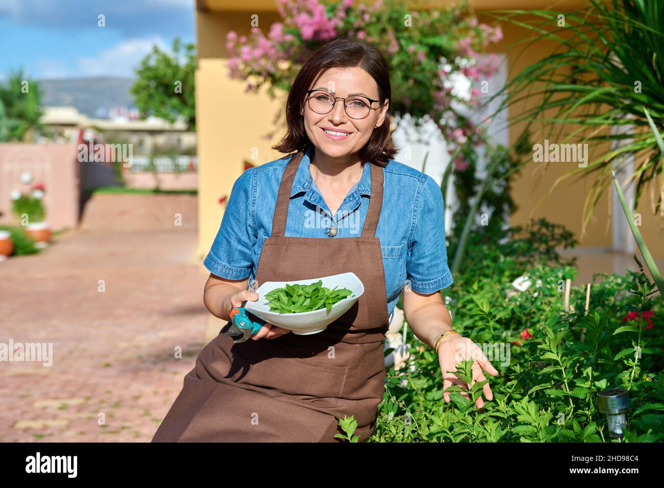 Middle aged woman with bowl of fresh mint, home herbal scented garden Stock Photo