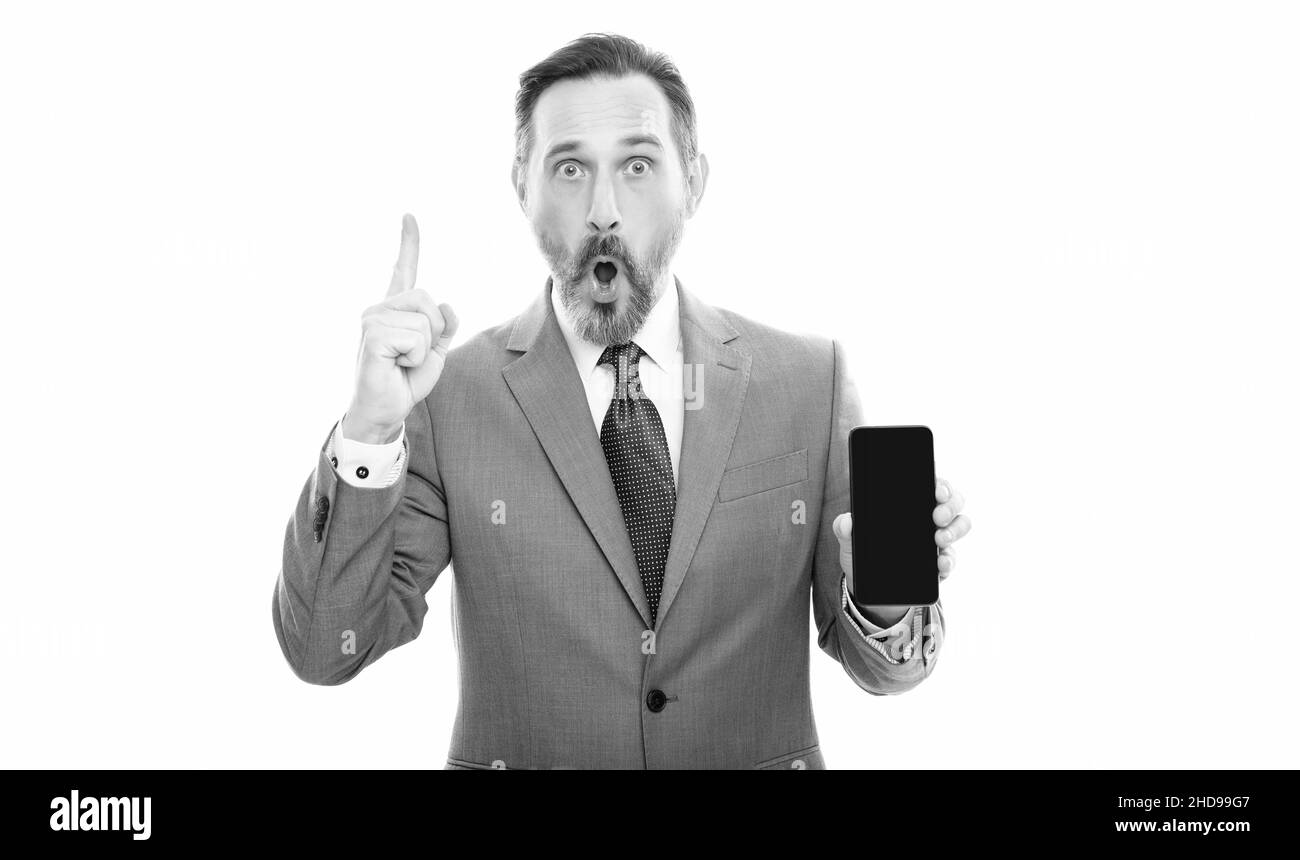 amazed grizzled ceo in suit presenting modern phone isolated on white copy space, advertisement Stock Photo