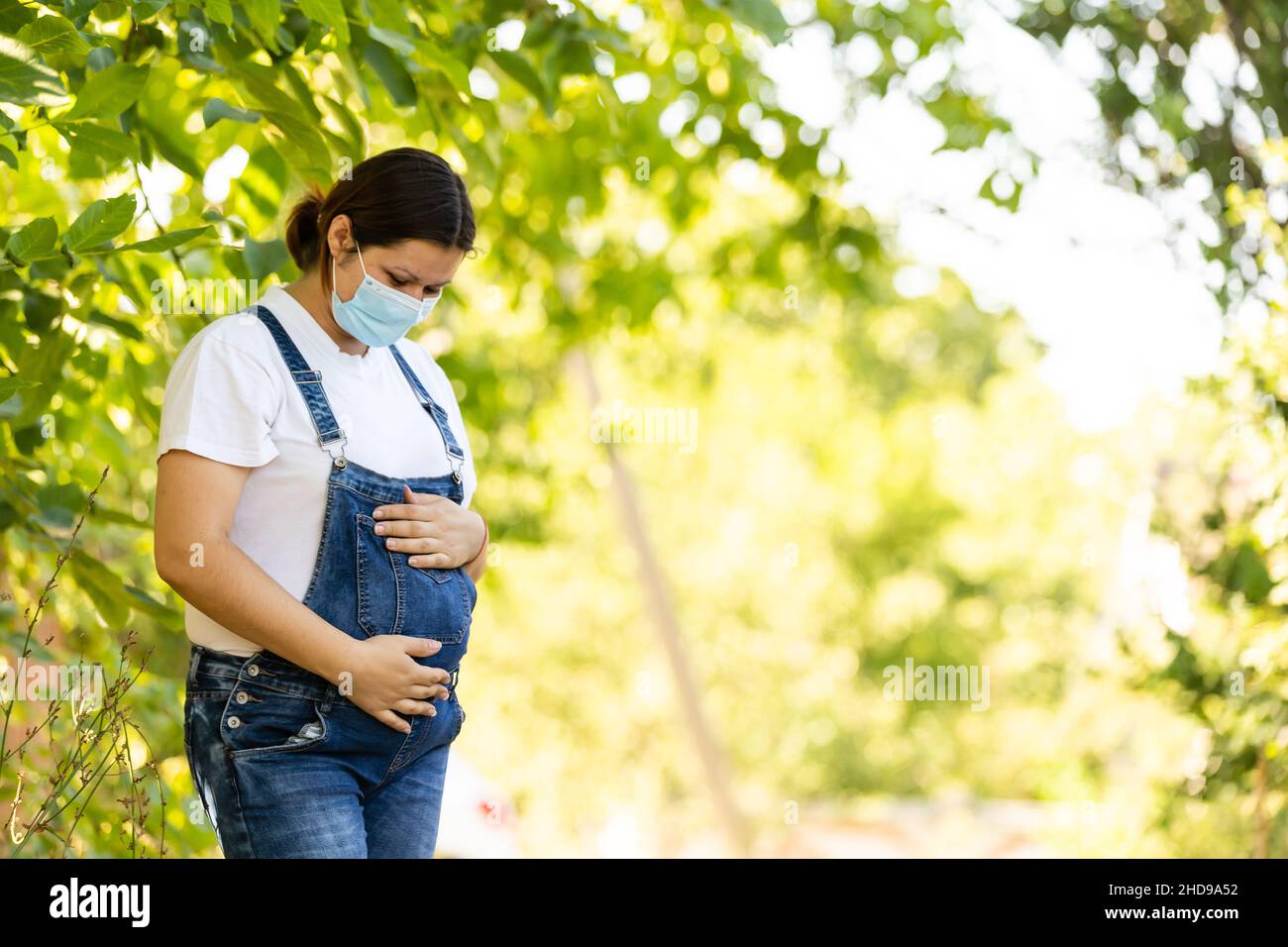 Young pregnant woman in protective medical mask covered her face. Virus