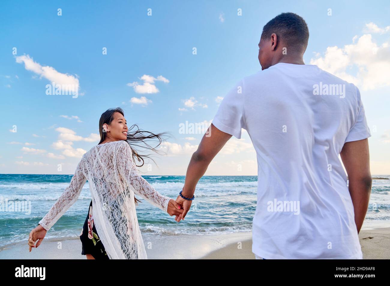 Loving happy couple walking holding hands on the beach Stock Photo