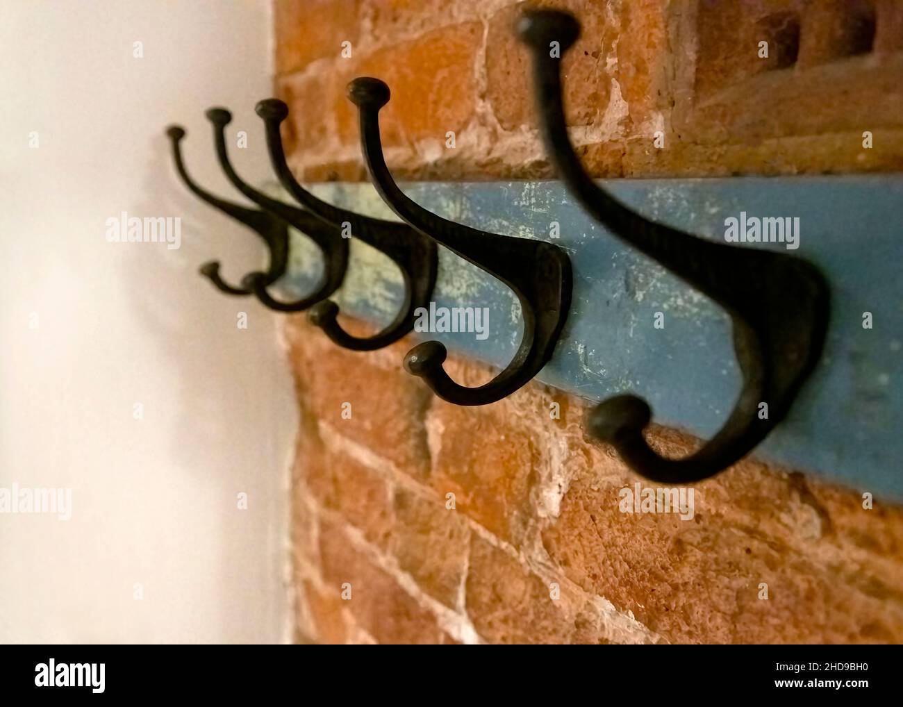 Wrought iron coat hangers place on old blue vintage wood hung on a brick textured wall with a blank leftside for copy space shot in selective focus wi Stock Photo