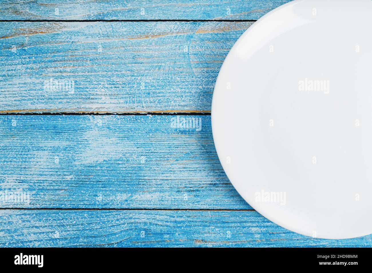 An empty round white plate on a blue wooden table. Top view Stock Photo