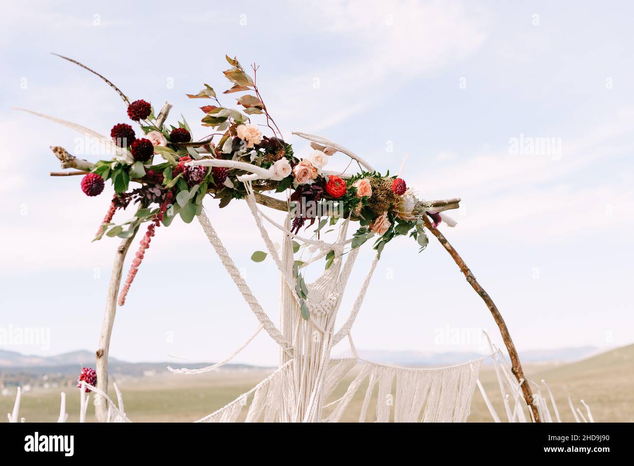 Wedding arch decorated with bright flowers and white macrame lace Stock Photo