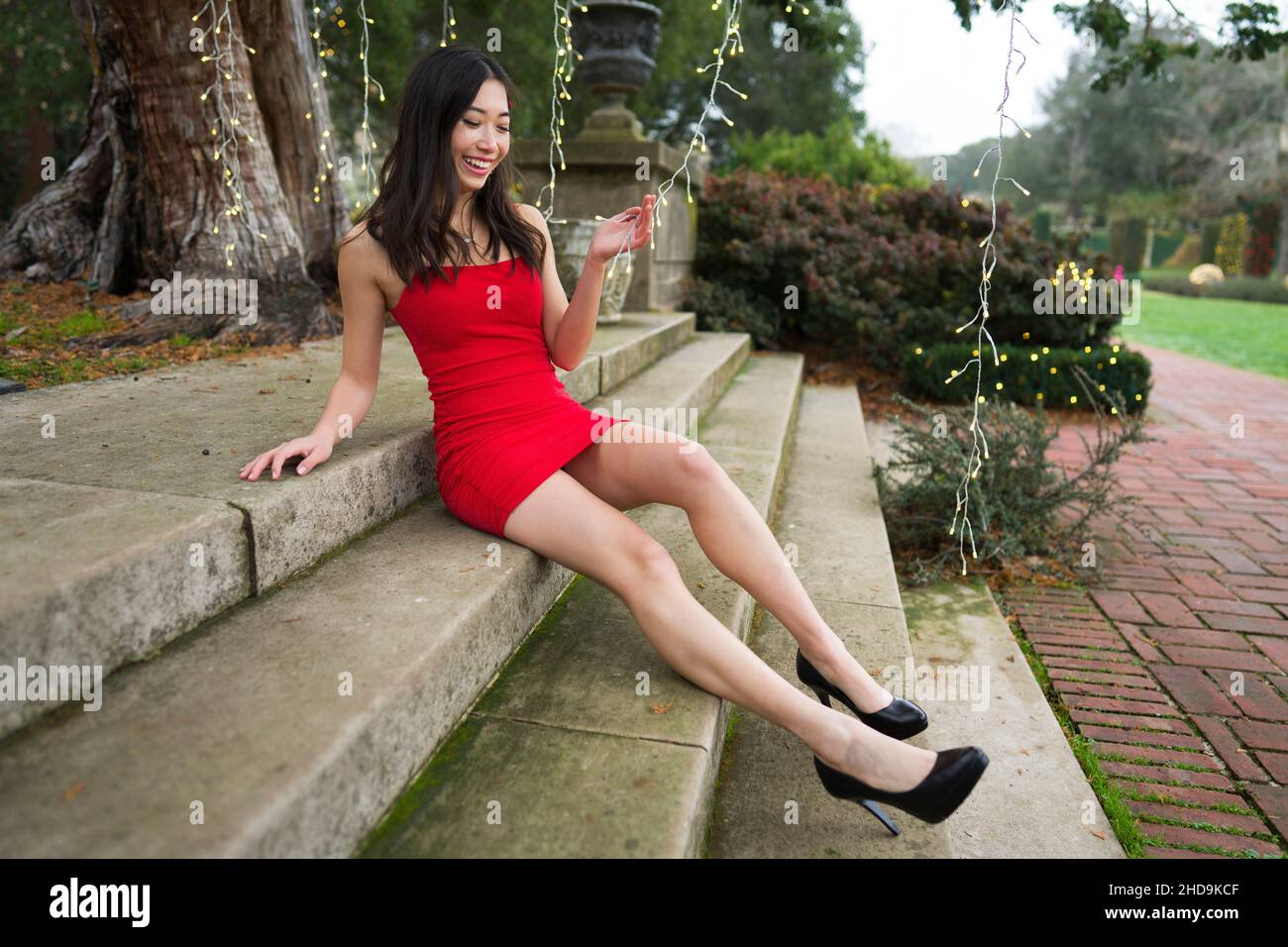 Young East Asian Woman in Red Party/Holiday Dress Lounging on Steps Playing  with Lights Stock Photo - Alamy