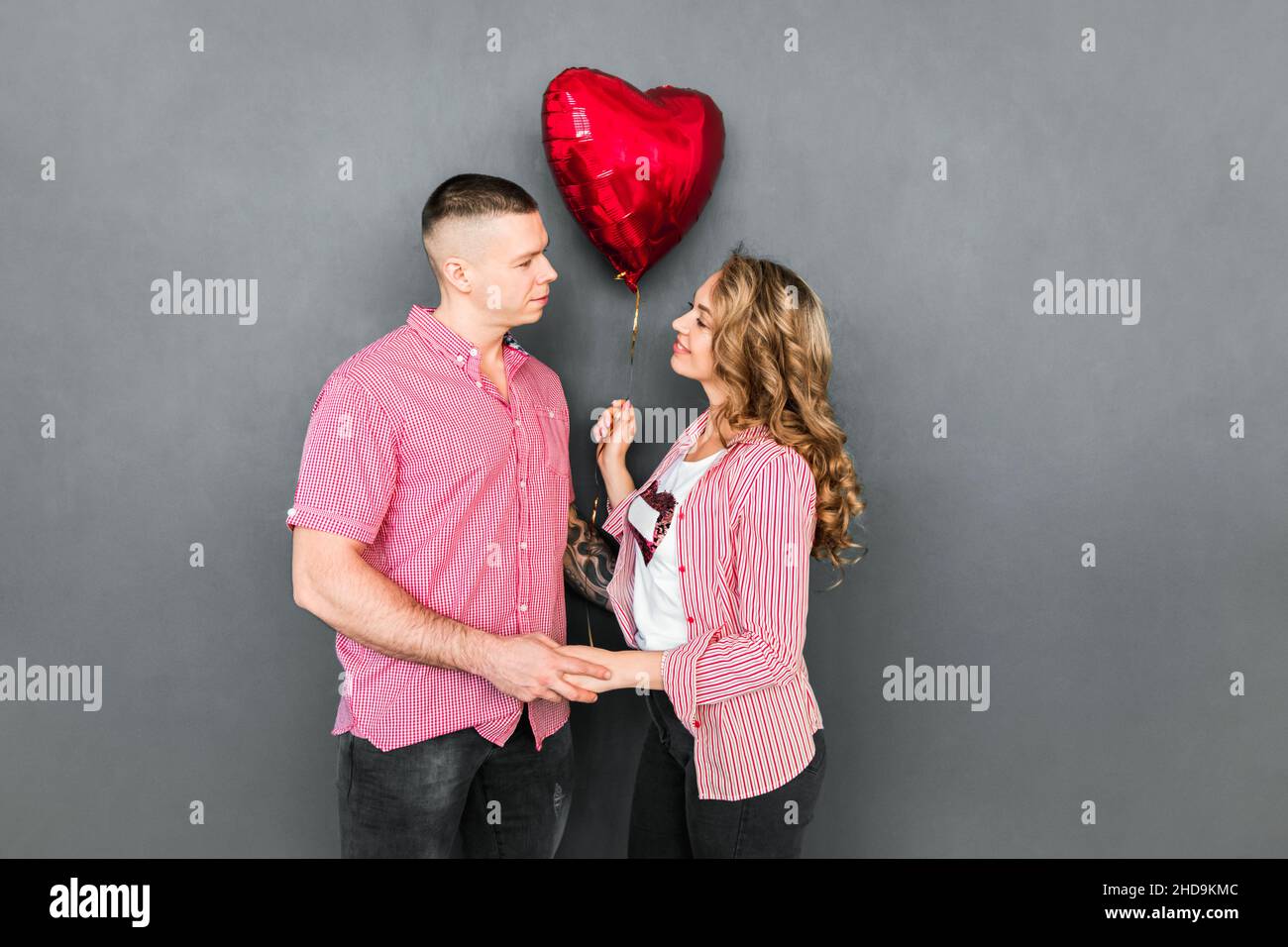 Beautiful couple holding heart balloon in their hands Stock Photo - Alamy
