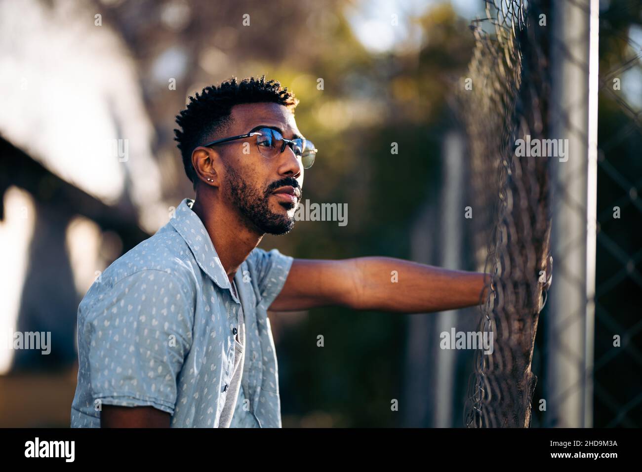 Handsome African American man leaning on a fence pensive Stock Photo