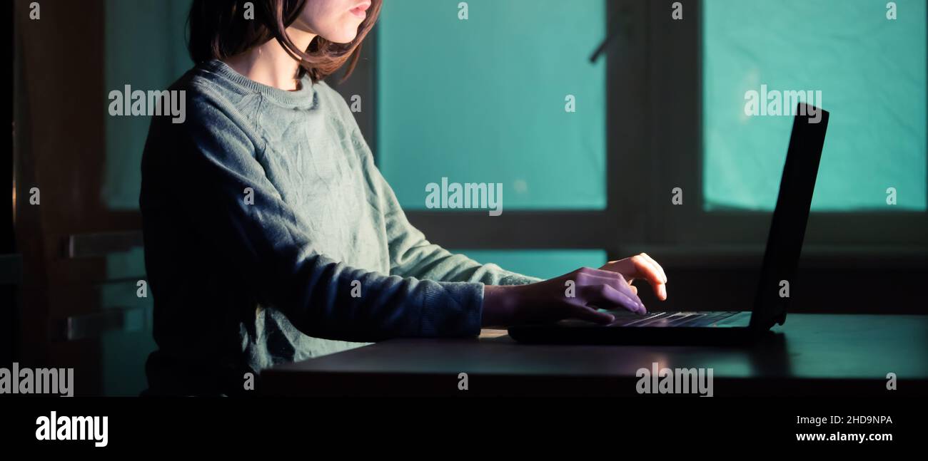 The girl works on the laptop at night. Stock Photo