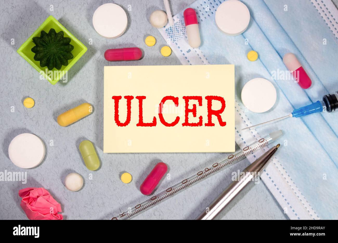 Medical and stomach ulcer symbol. Doctor hand. White card with the word 'ulcer'. Beautiful blue background. Doctor hand in blue glove. Medical and sto Stock Photo