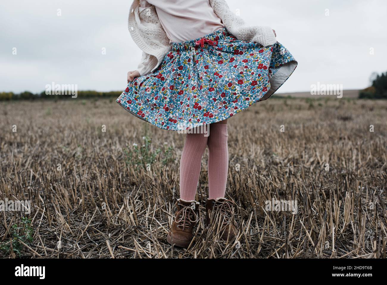 girl doing a curtsy whilst playing outside in a field Stock Photo
