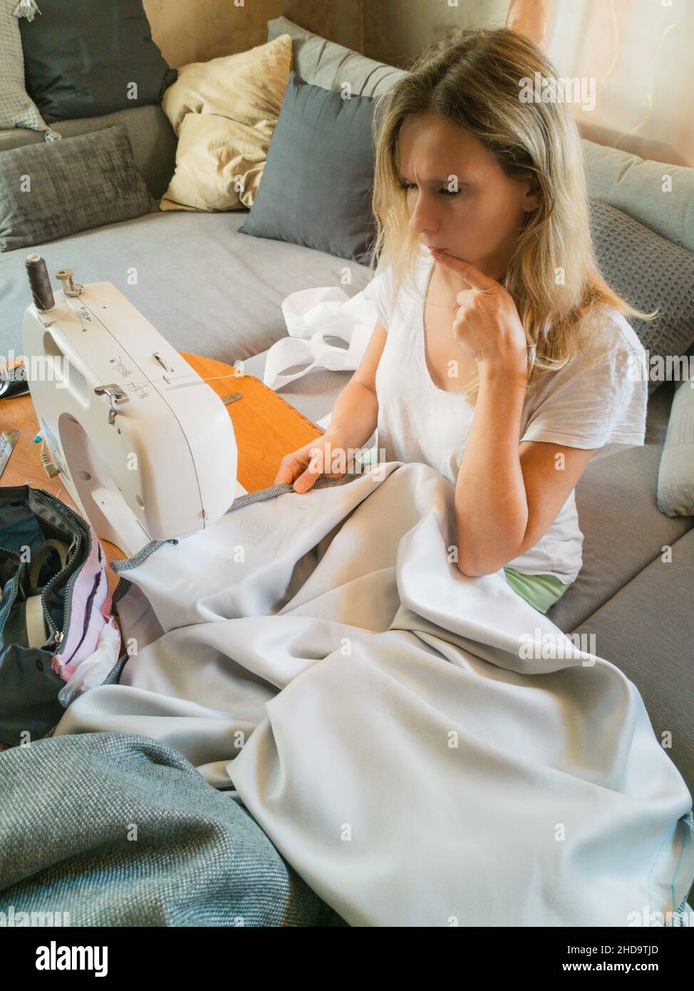 A beautiful, smiling young girl sewing on a sewing machine Stock Photo