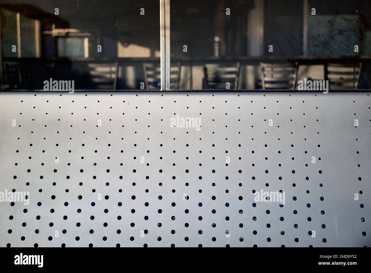 detail of steel seating with perforated grid with window in background Stock Photo