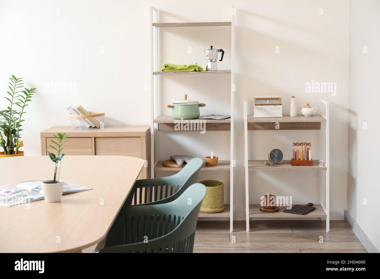 Interior of light dining room with table and shelving units Stock Photo ...