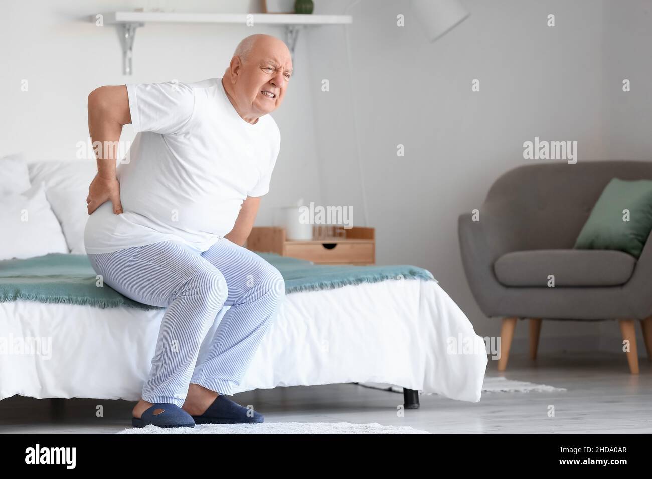Senior man suffering from back pain on bed at home Stock Photo - Alamy