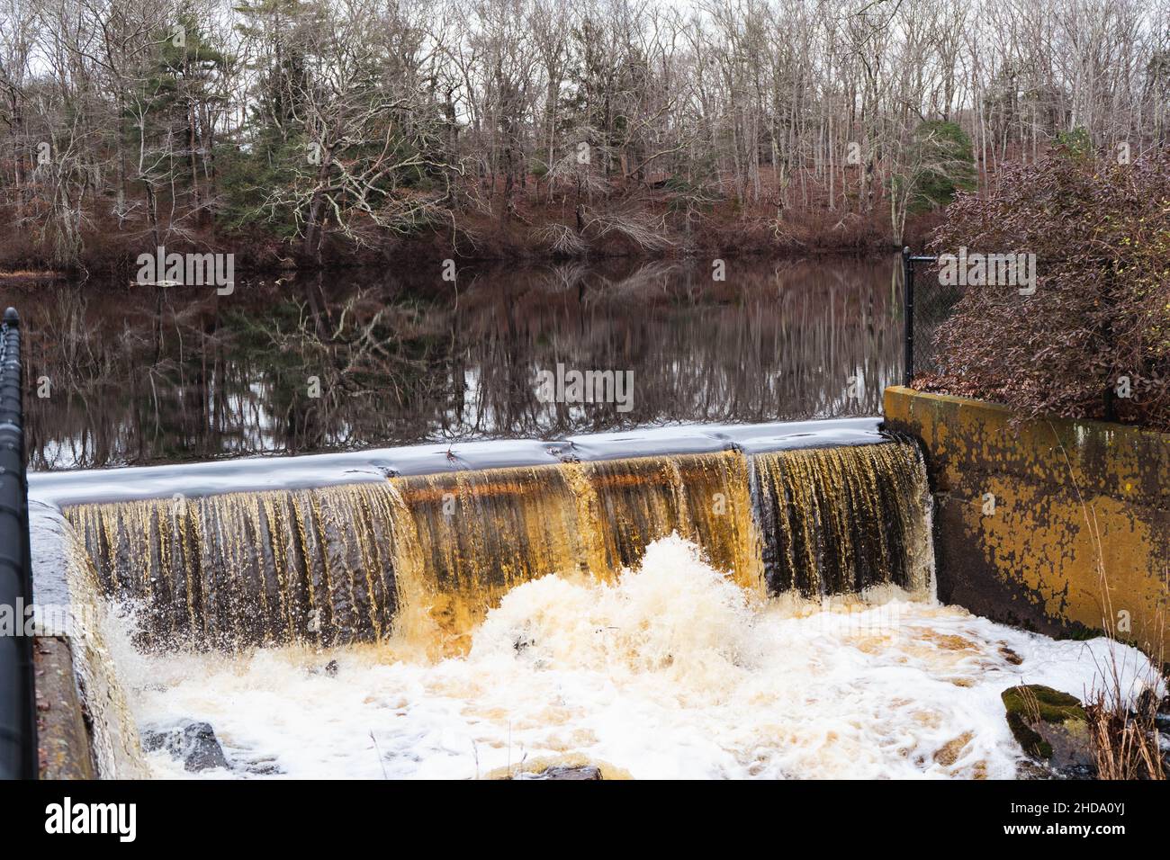 Dried Tree Leaves besides Flowing River and Man-made Dam. This photo was captured in white mountains. Stock Photo