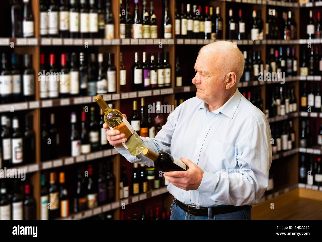 man chooses between red and white wine Stock Photo