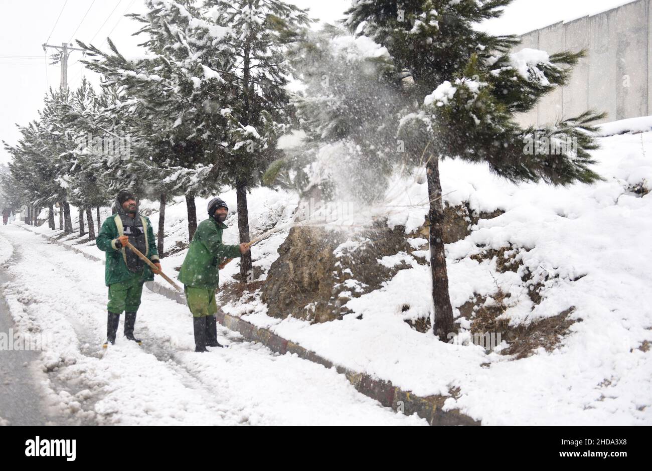Kabul, Afghanistan. 4th Jan, 2022. Afghan men clean the snow on the street in Kabul, capital of