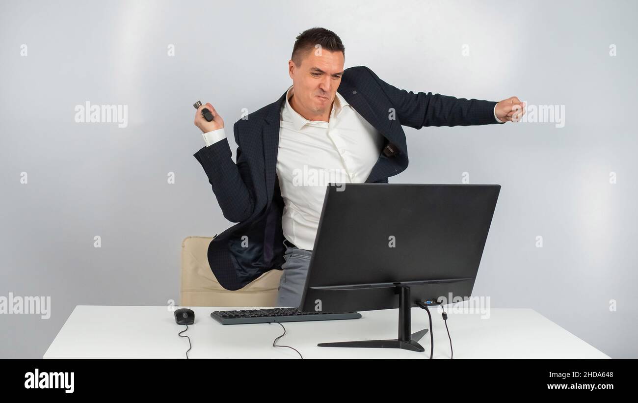 The man gets angry and smashes the monitor with a hammer. An office worker in a rage breaks the computer.  Stock Photo