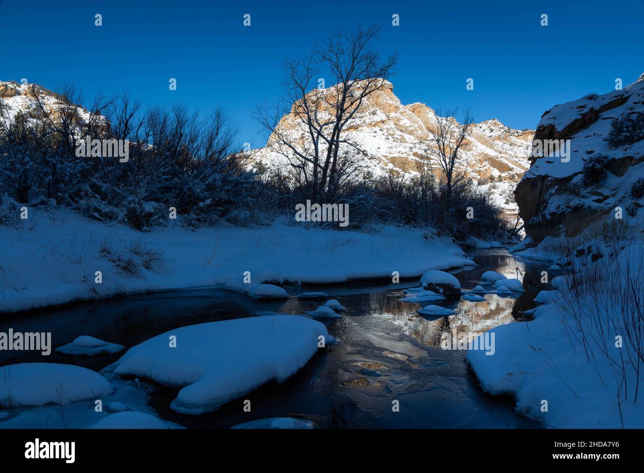 The icy waters of the Escalante River reflecting large sandstone