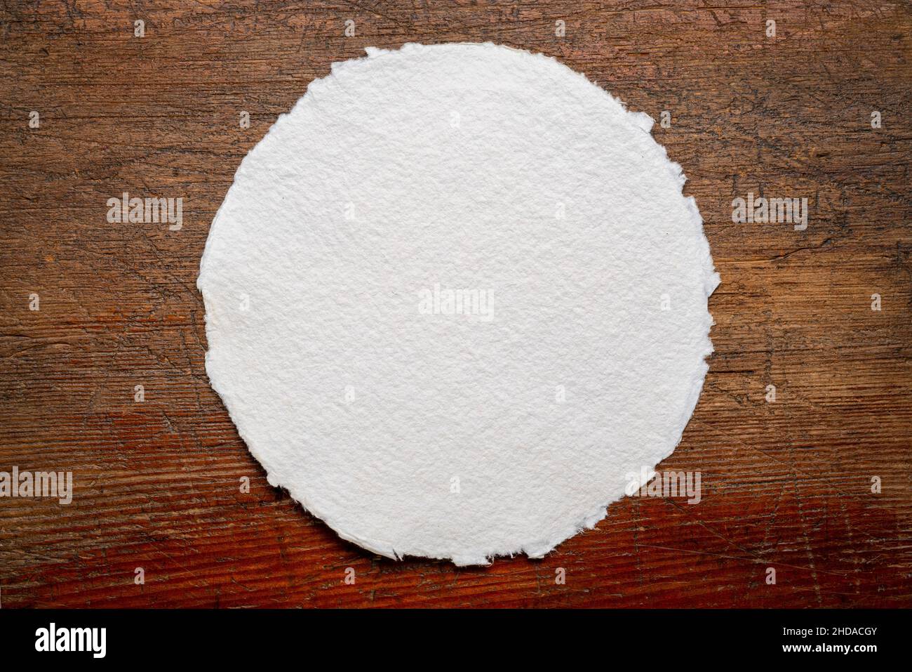 circular sheet of blank white watercolor paper against rustic weathered wood Stock Photo