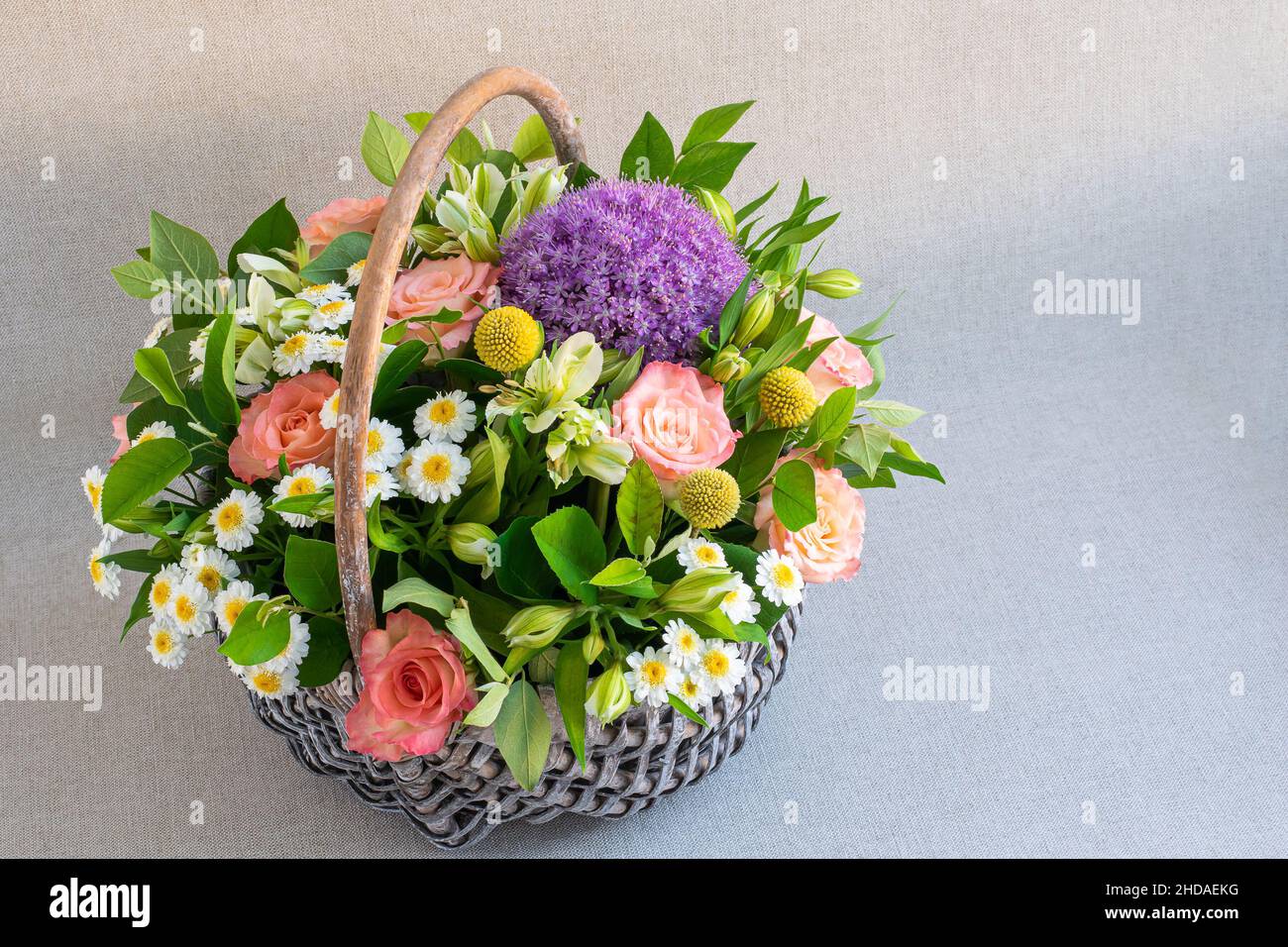 Delicate flowers in a wicker basket on light background Stock Photo