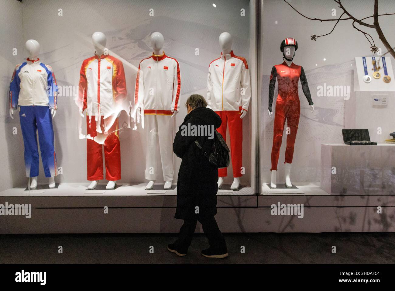 A woman looks at track suits worn by Chinese athletes at past Olympic Games at an exhibition at the Capital Museum ahead of the Beijing 2022 Winter Olympics in Beijing, China, January 5, 2022.   REUTERS/Thomas Peter Stock Photo