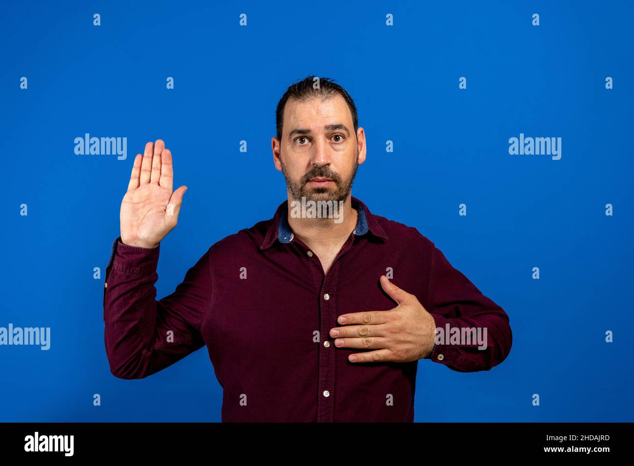 Young handsome man wearing casual shirt standing over isolated blue background. Swearing with hand on chest and open palm, making a loyalty promise Stock Photo