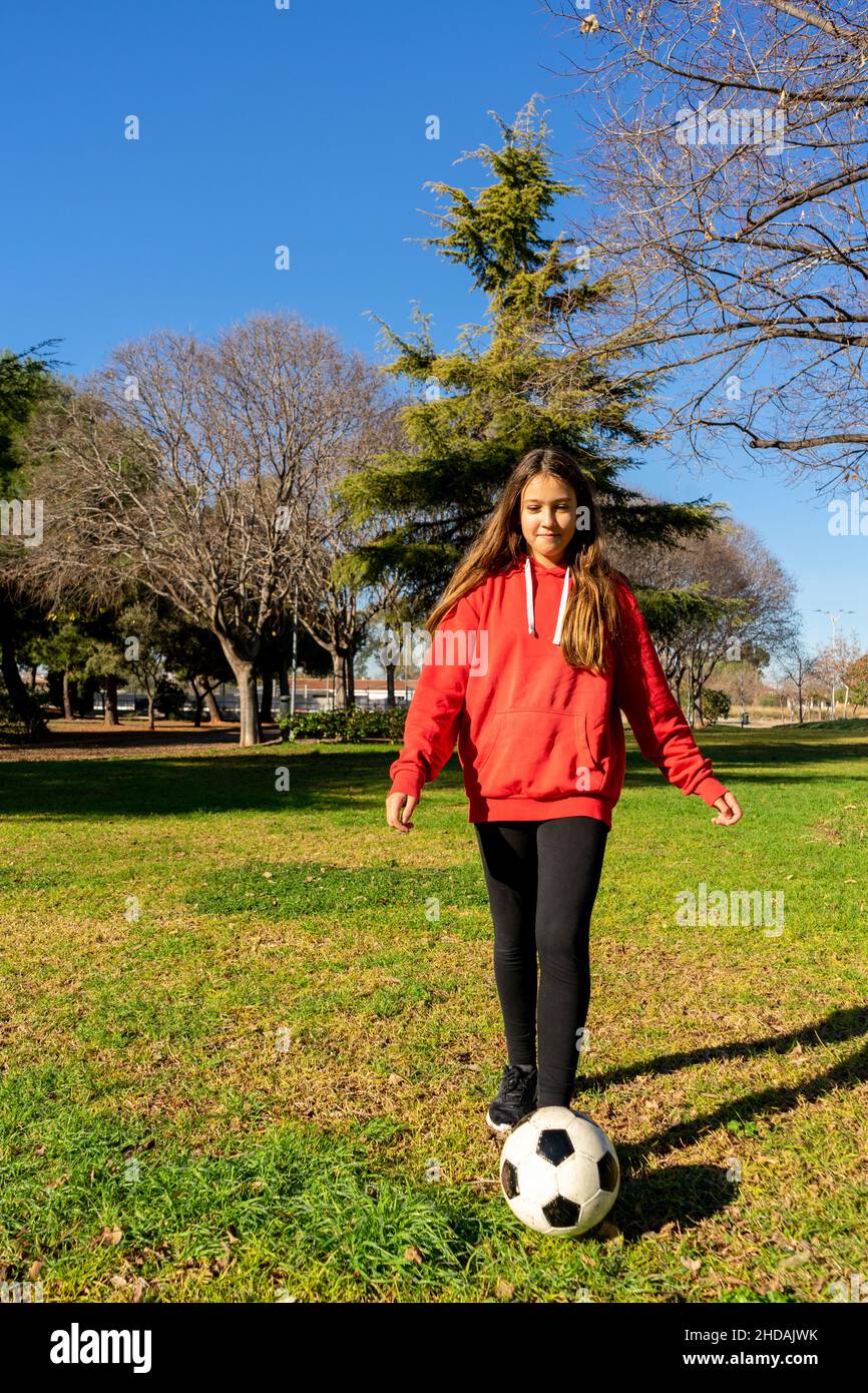 Beautiful little girl playing soccer in a nice park with natural grass ...