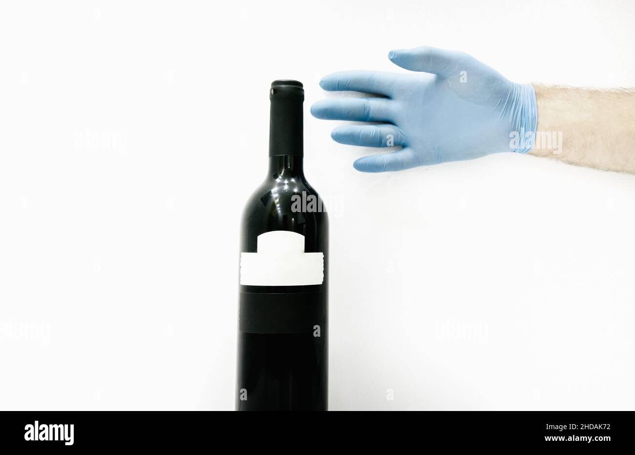 Hand with blue gloves reaching bottle of red wine. in white background