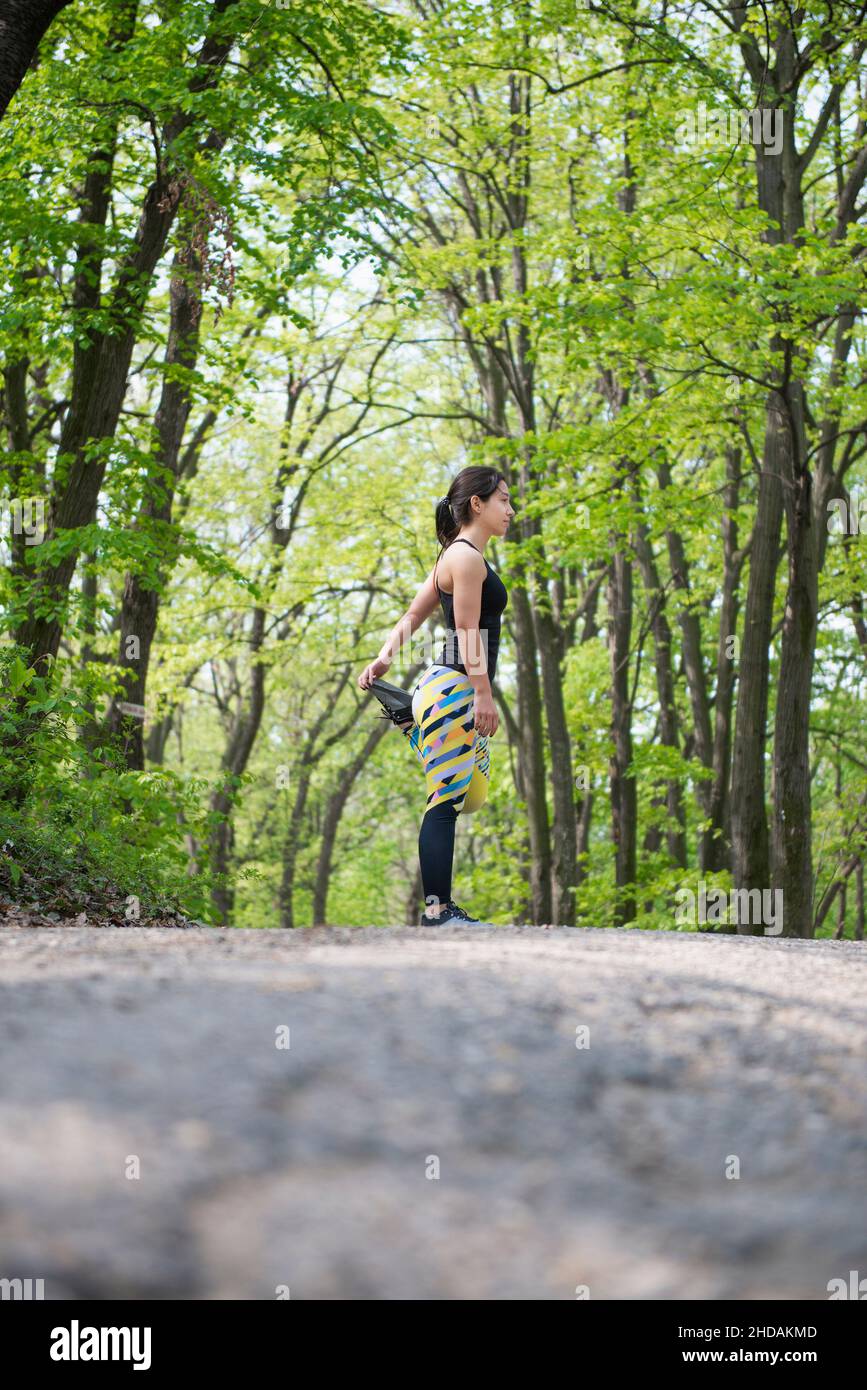 Female athlete stretching her legs before a morning workout in the woods Stock Photo