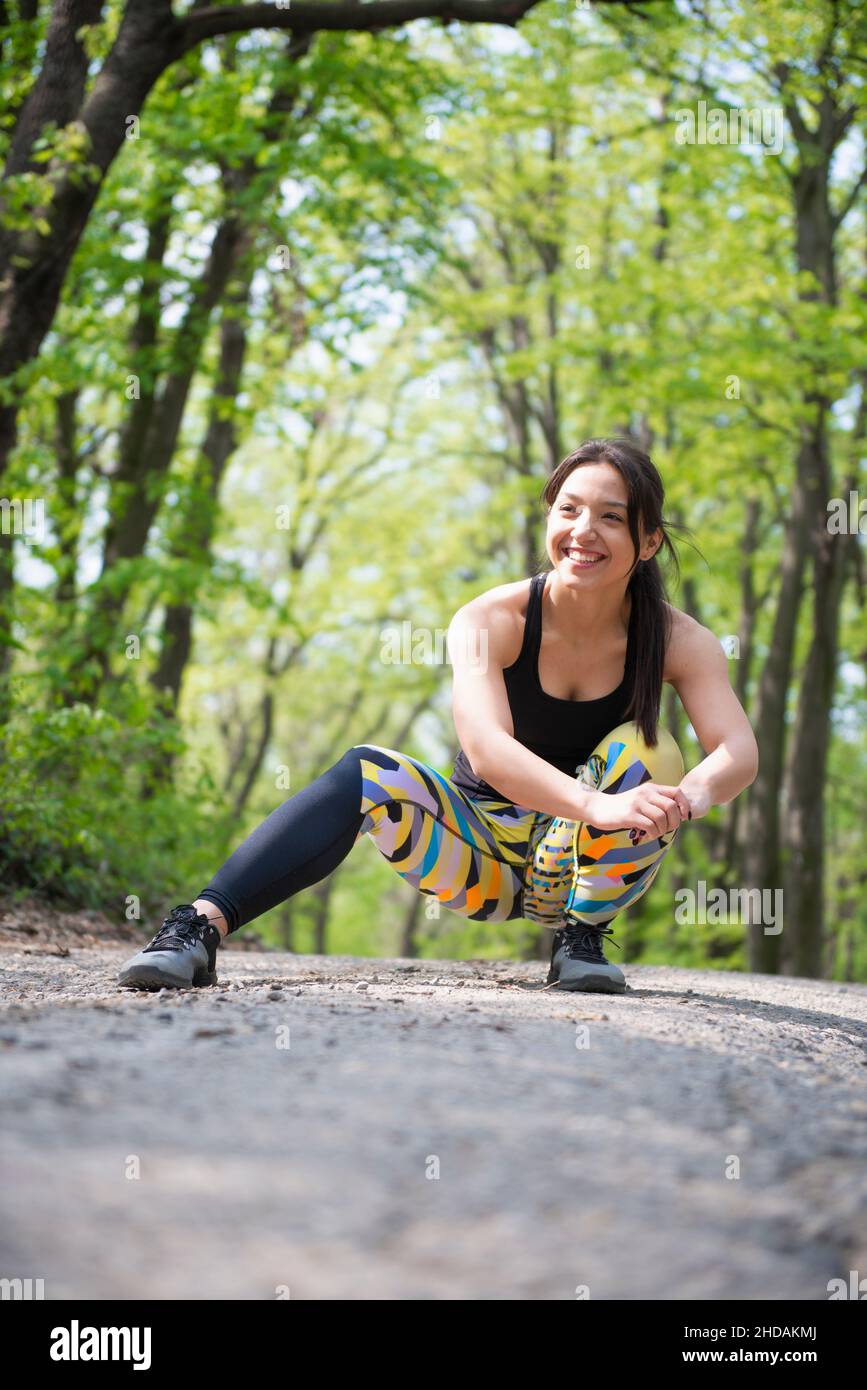 Joyful female athlete stretching her legs and having fun during her training in the nature Stock Photo