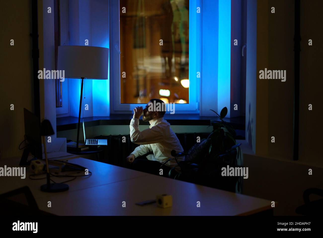 Tired programmer stay at work overtime at night before project deadline keep awake drinking coffee Stock Photo