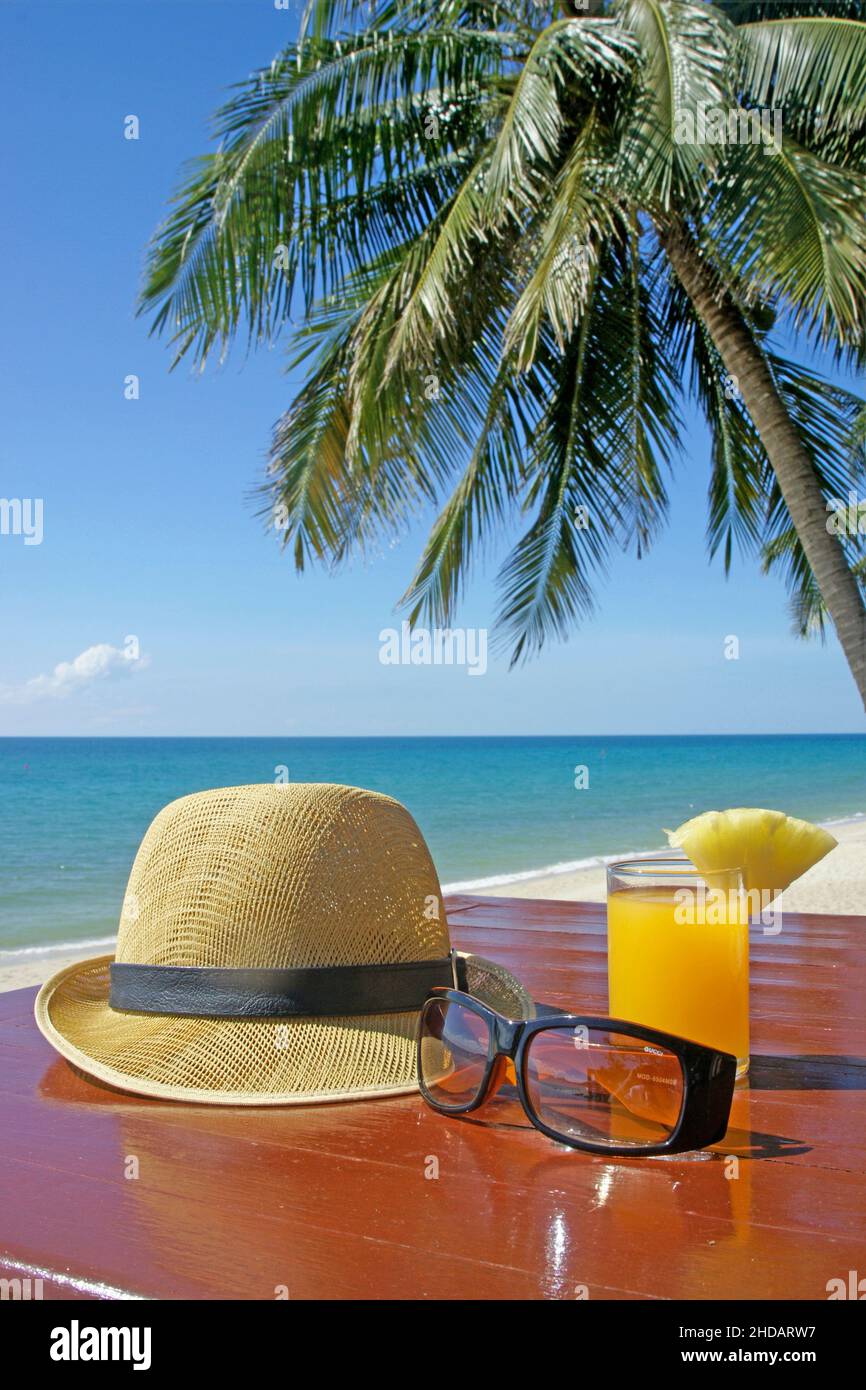 Sonnenhut mit Sonnenbrille und Fruchtsaft unter Palmen am Strand in ...