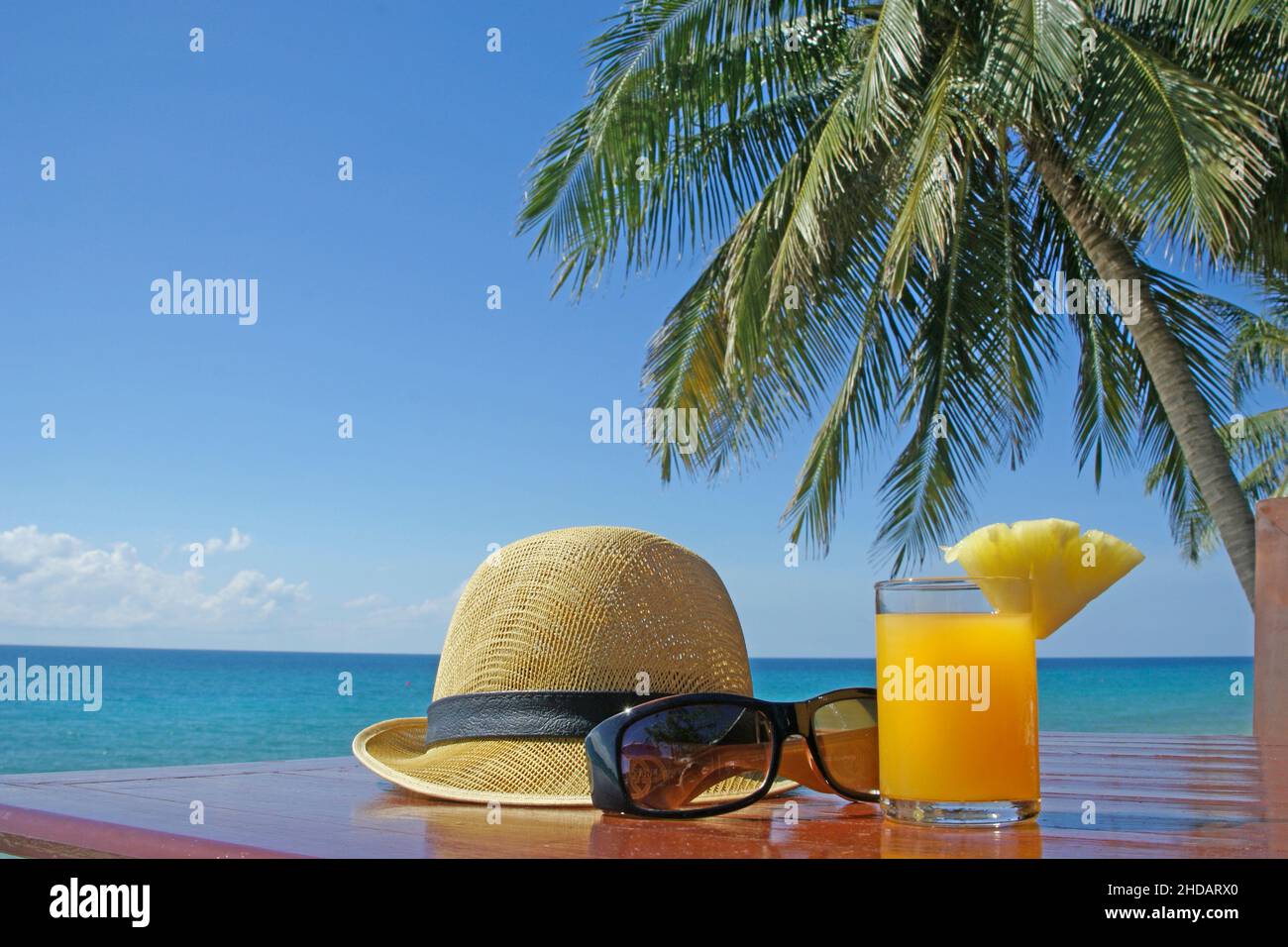 Sonnenhut mit Sonnenbrille und Fruchtsaft unter Palmen am Strand in Thailand Stock Photo
