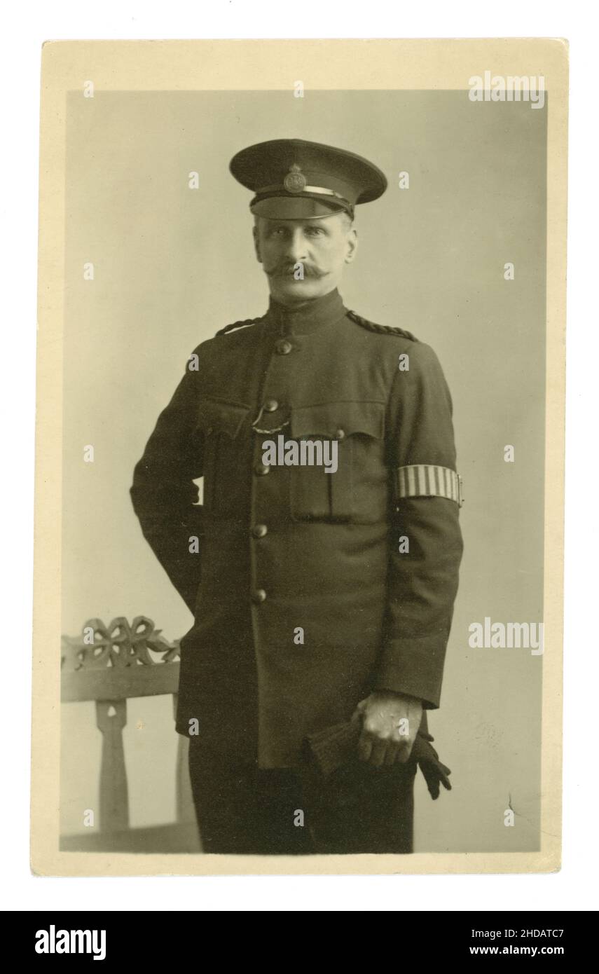 WW1 era postcard of a Special Constable (Specials) His police cap badge denotes he was a member of the "Metropolitan Special Constabulary"  He also wears a duty armband with vertical stripes, braided epaulettes. He is a handsome man with a "handlebar moustache". From E. Van Trolga's studios, Clapham or Putney area, London, UK . Circa 1916 Stock Photo