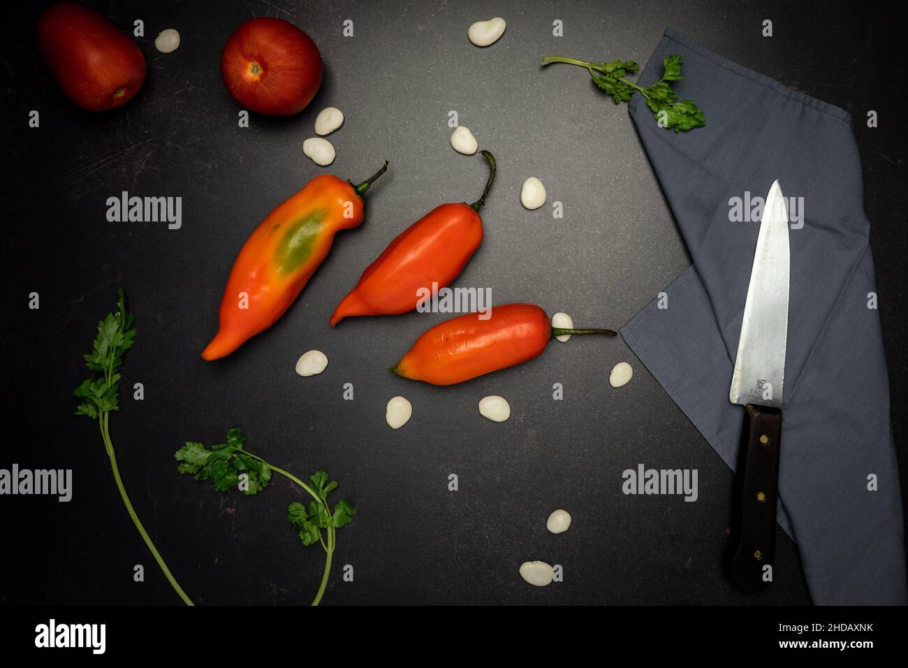 A top view of red chili peppers on a black messy kitchen table Stock Photo