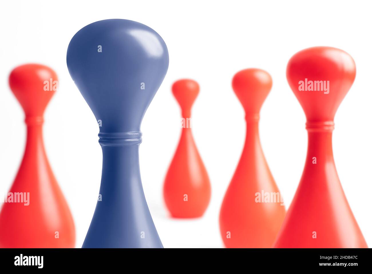 Blue skittle in the front and four red in the back. Teamwork with outstanding team member or leader. Dare to be different. Standing out from the crowd Stock Photo