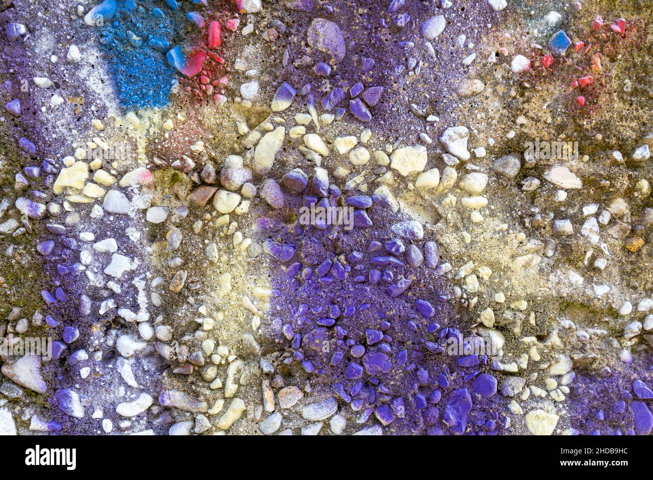View from above at horizontal picture of colored detail of exposed aggregate concrete with lilac as slightly dominant color. Stock Photo