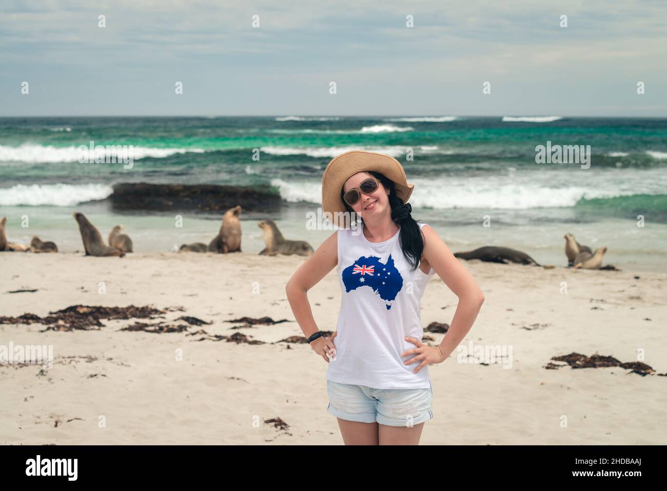 Happy smiling woman posing for a photo next to the sea lions at Seal Bay, Kangaroo Island, South Australia Stock Photo
