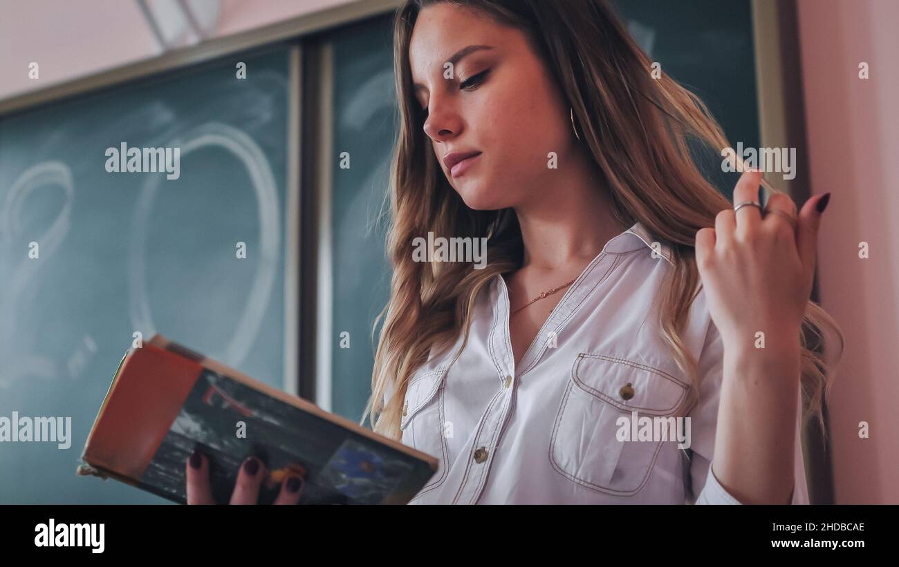 Cute schoolgirl reads a book in class Stock Photo - Alamy