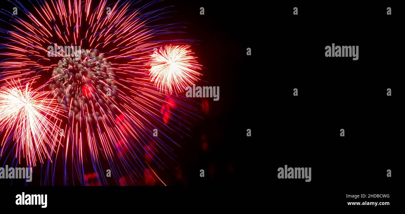 Flash of red and white fireworks on background black sky. Concept of holiday. Close-up, banner, copy space. Stock Photo