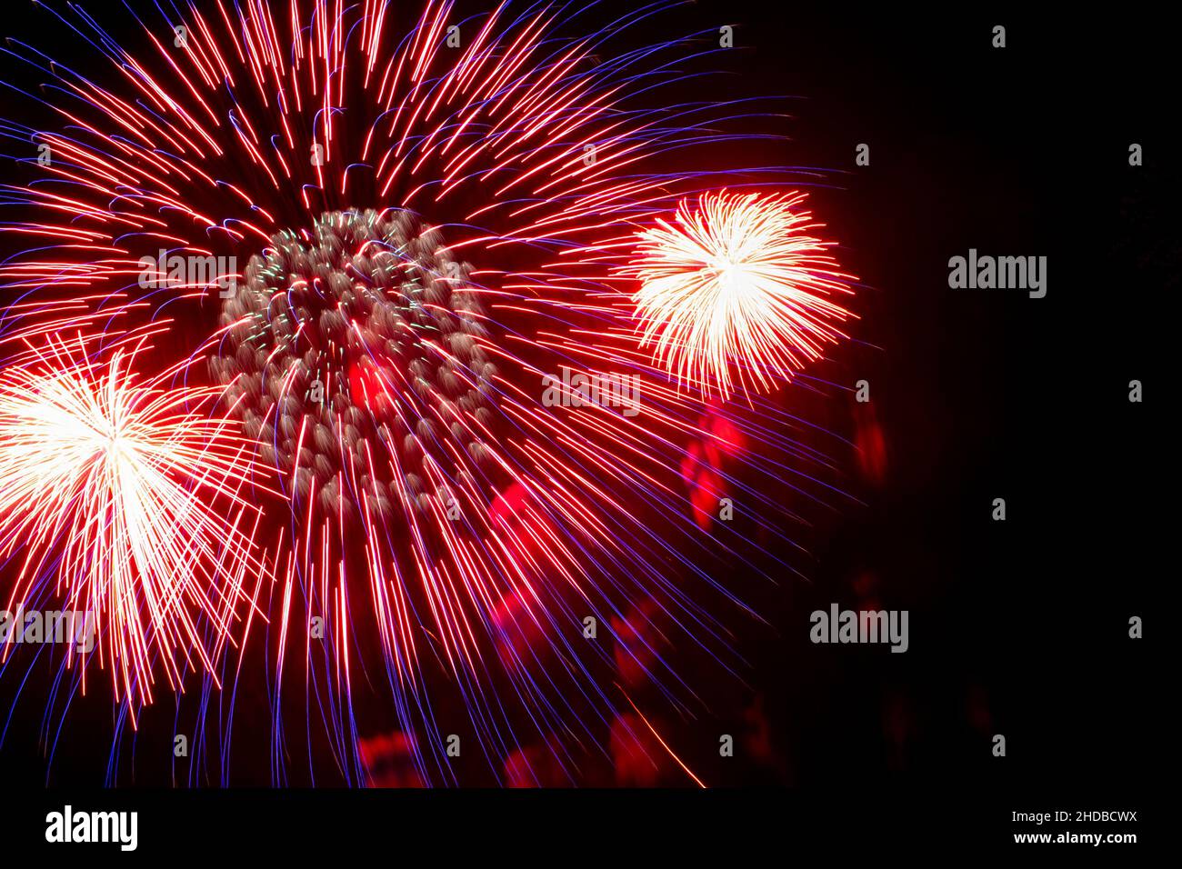 Flash of red and white fireworks on background black sky. Concept of holiday. Close-up Stock Photo
