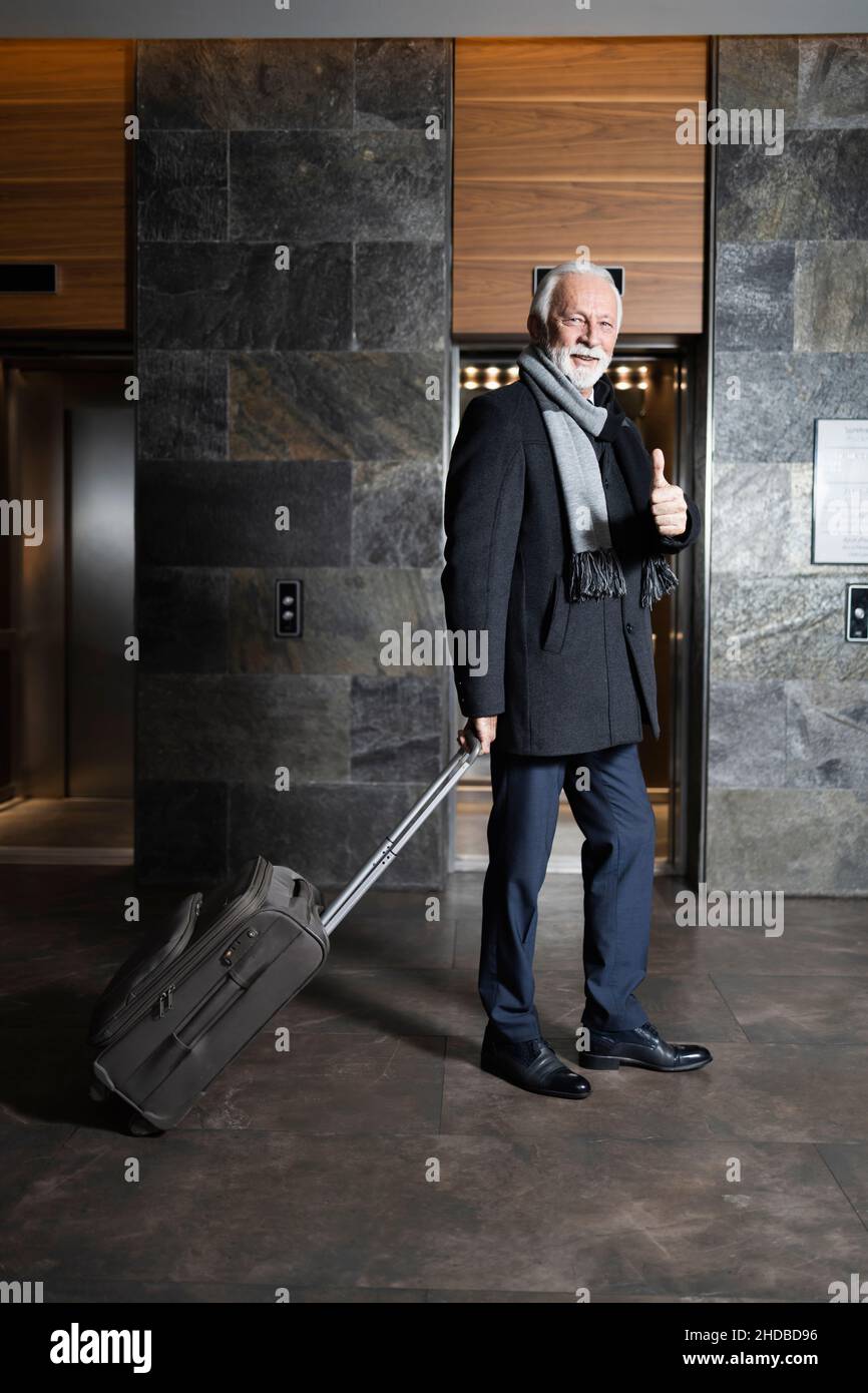 Older gentleman showing thumbs up in the hotel lobby Stock Photo