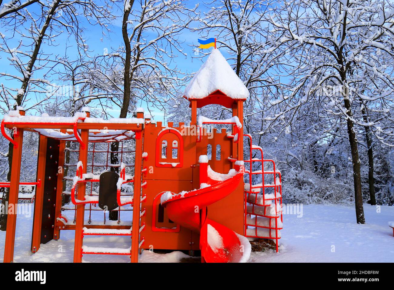 In the winter park, there is a red playground covered with snow. Children's slides and swings in winter. Dnipro city, Dnipropetrovsk, Ukraine Stock Photo